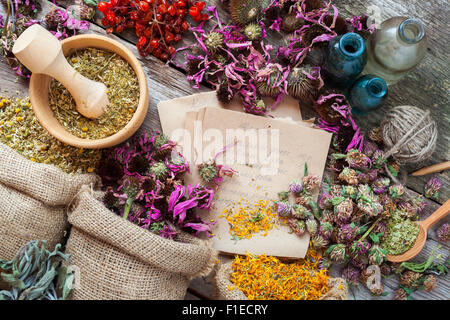 Heilkräuter in der Hessischen Taschen, hölzerne Mörser, Flaschen mit Tinktur, Kräutermedizin. Ansicht von oben. Stockfoto