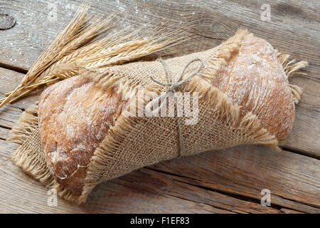 Frische hausgemachte Brot und Weizen Ohren auf alten Holztisch. Stockfoto