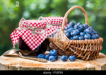 Korb mit reifen Blaubeeren und zwei Gläser Marmelade Stockfoto