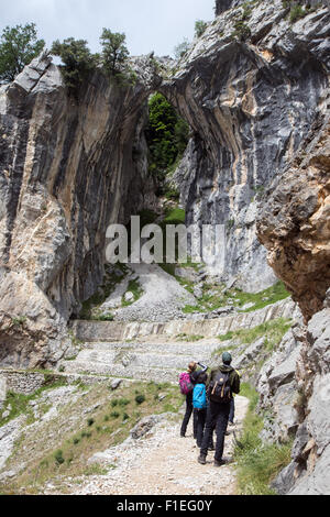 Wanderer stoppen, um ein natürliches Loch in den Kalkstein auf dem Weg durch die Schlucht kümmert sich in der Nähe von Poncebos in den Picos de Europa anzeigen Stockfoto