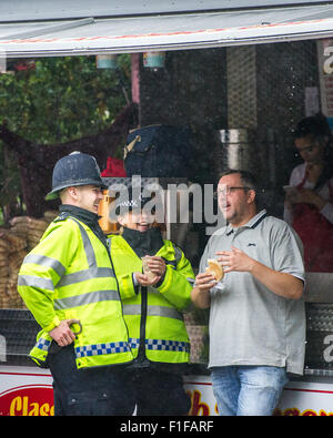 London, UK. 31. August 2015. Metropolitan Police Officers genießen Sie ein heißes Getränk und etwas Schutz in einem Hot-Dog-Stand während der Notting Hill Carnival 2015. Bildnachweis: Pete Maclaine/Alamy Live-Nachrichten Stockfoto