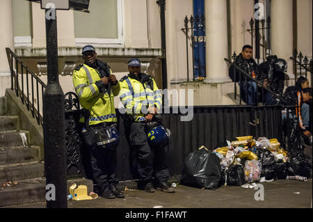 London, UK. 31. August 2015. Zwei Polizisten in Kampfmontur stehen neben einem Haufen Müll nach der Notting Hill Carnival 2015. Bildnachweis: Pete Maclaine/Alamy Live-Nachrichten Stockfoto