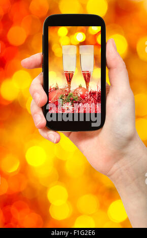 Mann nimmt Foto von Weihnachten Stillleben - zwei Gläser Champagner mit rot und gelb verwischt Weihnachten Lichter Bokeh Hintergrund Stockfoto