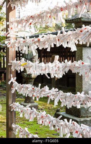 Blick entlang des Rahmens Arbeiten mit Strings ausgestreckt und viele Japanische omikuji, manchmal auch als "O-mikuji Pech fortune Papiere, Streifen, auf gebunden. Stockfoto