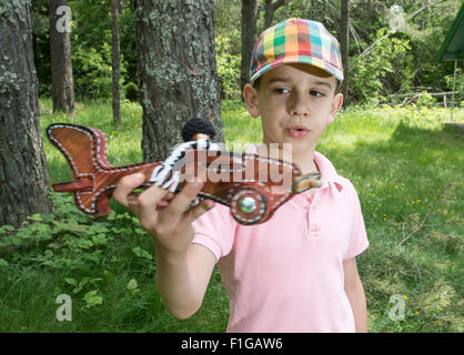 Kinderspiel mit einem hölzernen Flugzeug in den Bergen. Wald Stockfoto