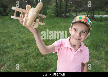 Kinderspiel mit einem hölzernen Flugzeug in den Bergen. Wald Stockfoto