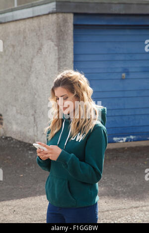 Ein 16-jähriger Teenager mit einem Handy draußen auf der Straße. Stockfoto