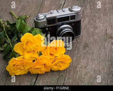 gelbe Rosen und Retro-die Kamera hinter ihnen auf einem Tisch Stockfoto