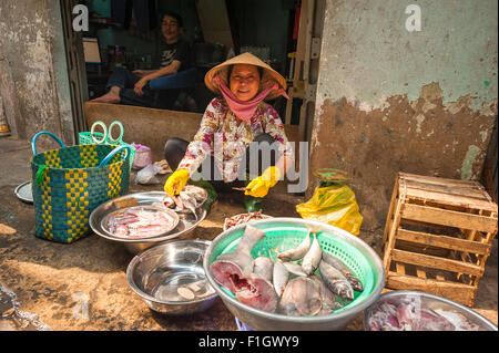 Vietnam lächelnde Frau, in Ho Chi Minh City eine vietnamesische Frau lächelt, als sie ihren Fisch auf einem Bürgersteig in der Nähe von den Binh Tay Markt abgewürgt. Stockfoto