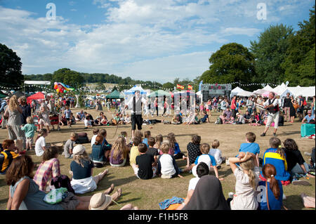 Familien beobachten ein Balanceakt in der Sommersonne von Garküchen und Zelten am Hafen Eliot Festival Cornwall Stockfoto