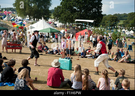 Familien beobachten ein Balanceakt in der Sommersonne von Garküchen und Zelten am Hafen Eliot Festival Cornwall Stockfoto