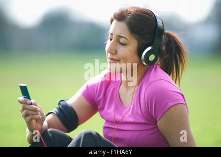 Reife Frau Übung Pause im Park Auswahl Musik vom MP3-player Stockfoto