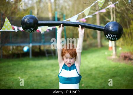 Kleiner Junge im Freien so tun Hantel heben Stockfoto