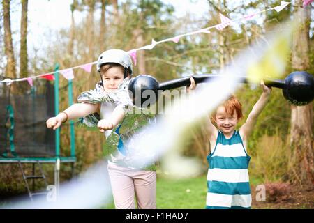 Kleine Kinder tragen Kostüme, spielen im Garten Stockfoto