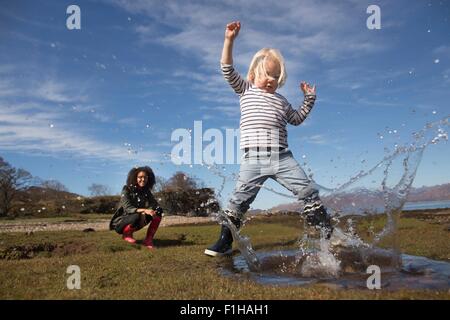 Junge in Pfütze planschen Stockfoto