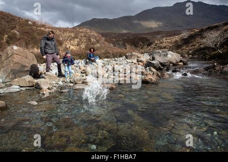 Familie Steinewerfen im Teich, Fairy Pools, Isle Of Skye, Hebriden, Schottland Stockfoto