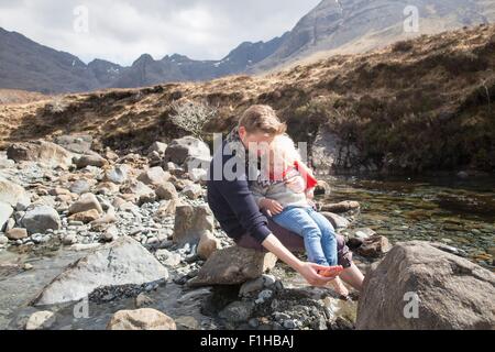 Vater und Sohn sitzen auf Felsen, Fairy Pools, Isle Of Skye, Hebriden, Schottland Stockfoto