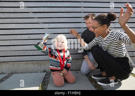 Junge hält Trophäe, Mutter jubeln Stockfoto