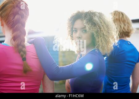 Rückansicht der drei Frauen trainieren zusammen mit einer Frau, Blick in die Kamera Stockfoto