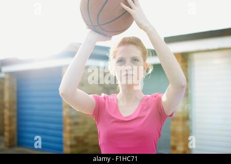 Porträt der Frau hält Basketball über Kopf Stockfoto