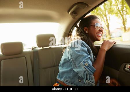 Junge Frau mit Sonnenbrille Blick aus dem Autofenster Stockfoto