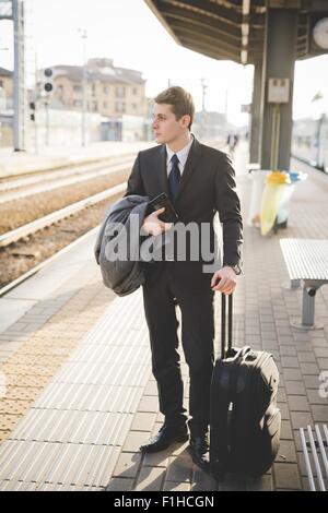 Junger Geschäftsmann Pendler am Bahnsteig mit Koffer. Stockfoto