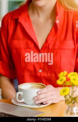 Nahaufnahme der junge Frau in Café Kaffee zu trinken, während Sie Laptop benutzen beschnitten Stockfoto