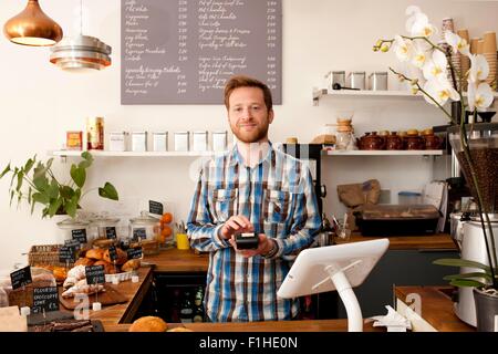 Porträt des Café Kellner mit Karte Maschine hinter Theke Stockfoto