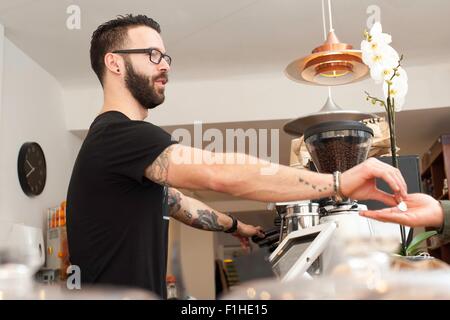 Cafe Kellner Übergabe Münzen Kunden hinter Theke Stockfoto