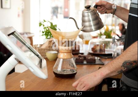 Händen des Café Kellner gießt kochendes Wasser in Topf Filterkaffee Stockfoto