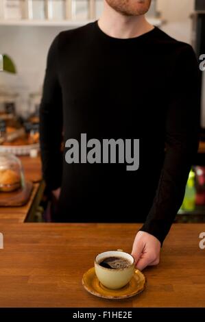 Schuss des Café Kellner servieren frischen Kaffee beschnitten Stockfoto