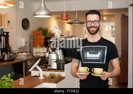 Porträt des Café Kellner servieren Tassen Kaffee Stockfoto