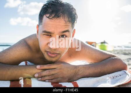 Porträt des jungen Mannes, Sonnenbaden am Strand von Waikiki, Hawaii, USA Stockfoto