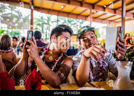 Zwei junge Männer lesen Menü in Polynesian Cultural Center, Hawaii, USA Stockfoto