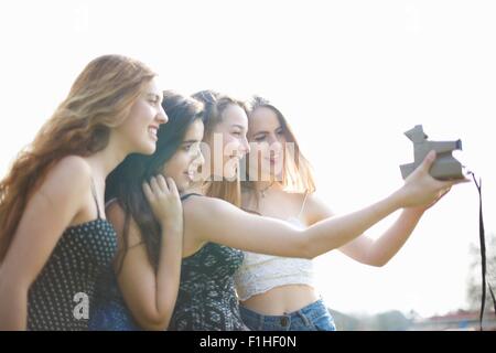 Vier Teenager Mädchen, die die Sofortbildkamera Selfie in park Stockfoto