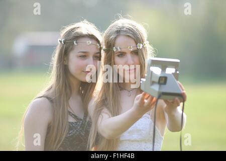 Zwei Mädchen im Teenageralter im Park unter Sofortbildkamera selfie Stockfoto