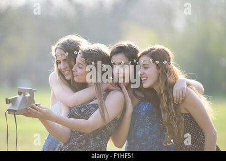 Vier Mädchen im Teenageralter im Park unter Sofortbildkamera selfie Stockfoto