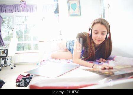 Teenager-Mädchen Vinyl Plattencover zu betrachten, während Sie Kopfhörer im Schlafzimmer lauschen Stockfoto