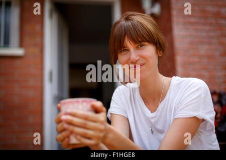 Mitte Erwachsene Frau sitzen duftenden Lavendel, lächelnd in die Kamera Stockfoto