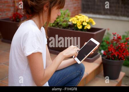 Seitenansicht der Mitte Erwachsene Frau sitzen im Freien mit digital-Tablette Stockfoto