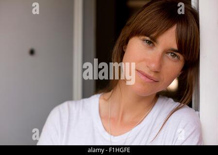 Porträt von Mitte Erwachsene Frau lehnte sich gegen Türrahmen, Blick in die Kamera Stockfoto