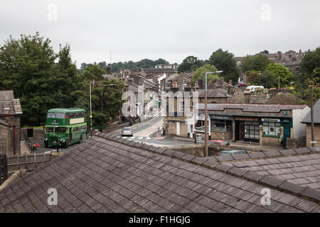 Ansicht von West Yorkshire Dorf von Haworth blickte Bahnhofstraße mit einem Oldtimerbus geparkt vor dem Bahnhof Stockfoto