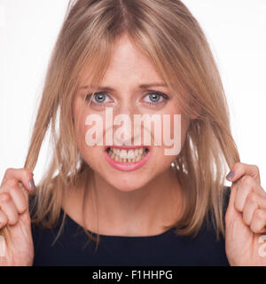 Blonde Frau ziehen ihr Haar mit frustration Stockfoto
