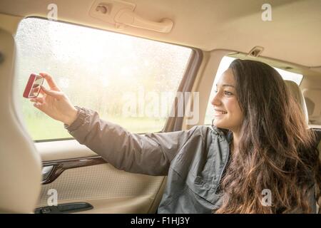 Teenager-Mädchen unter Smartphone Selfie auf dem Auto Rücksitz Stockfoto