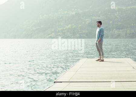 Junger Mann mit Blick vom Pier, Mergozzo See, Verbania, Piemont, Italien Stockfoto