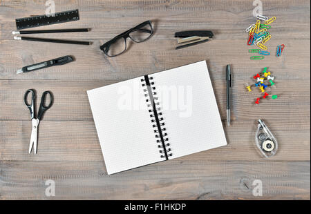 Büro- und Schulbedarf liefert über hölzernen Schreibtisch-Hintergrund. Aufgeschlagene Buch und Schreib-tools Stockfoto