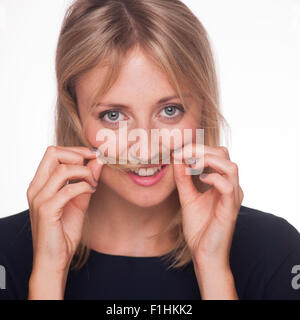 blonde Frau mit langen Haaren, die Umsetzung Haare über ihre Lippen zu einem Schnurrbart. Stockfoto