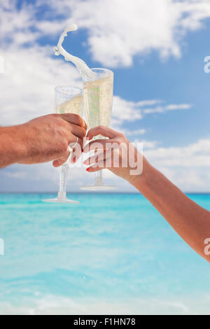 Klingende Gläser mit Champagner am Sandstrand und Meer Hintergrund, geringe Bautiefe Stockfoto