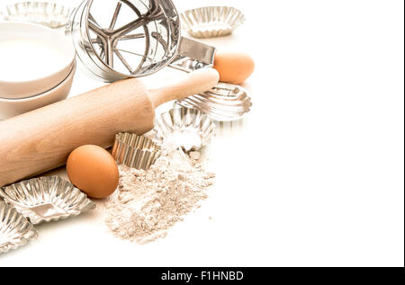 Backen, Zutaten und Maut für die Teigbereitung. Mehl, Eiern, Nudelholz und Ausstechformen auf weißem Hintergrund Stockfoto