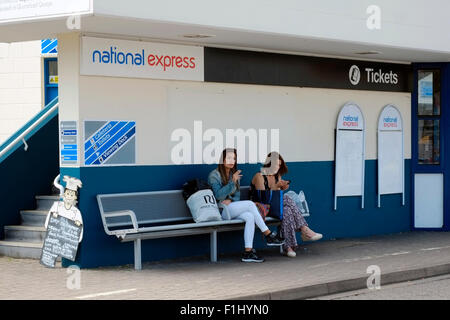 zwei Frauen sitzen außerhalb der national express Coach station an den harten interchange Portsmouth England uk Stockfoto